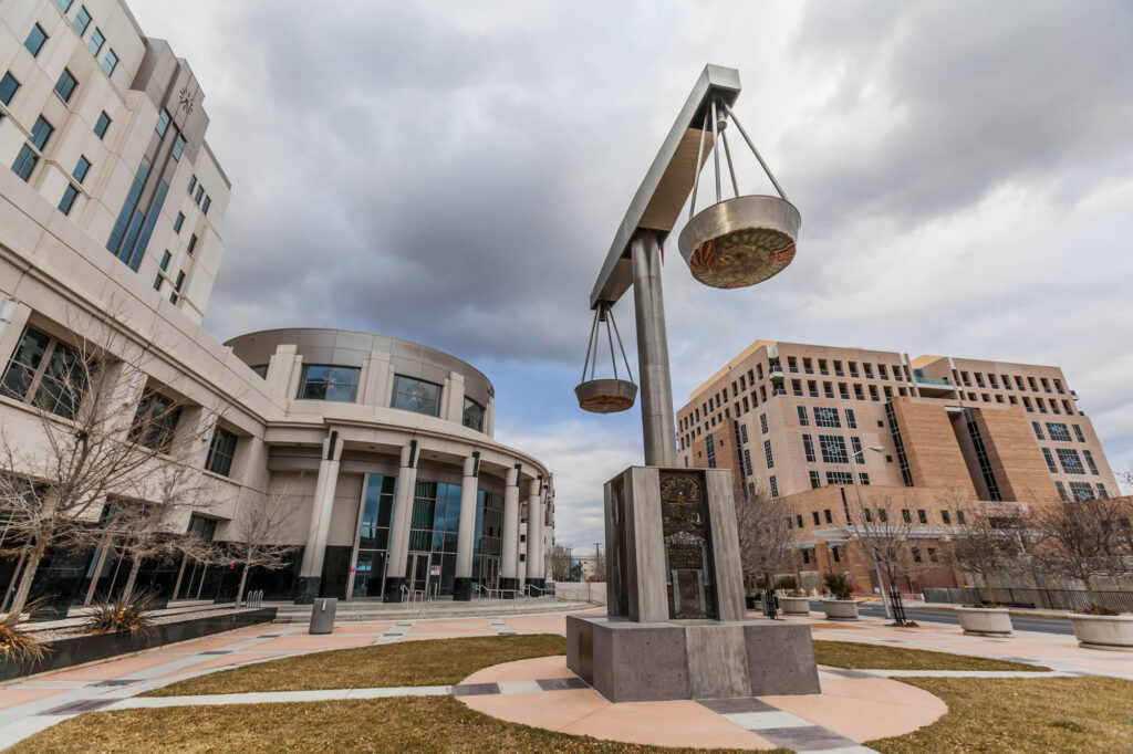 A statue of the scales of justice in front of a building.