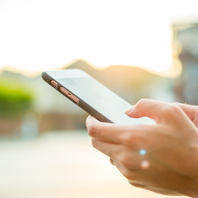 A person holding their cell phone in one hand and another hand on the other.
